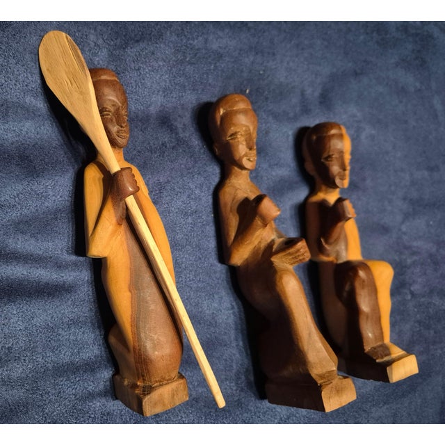 These three vintage hand-carved folk art figurines depict stylized human forms sculpted out of a single block of dynamic,...