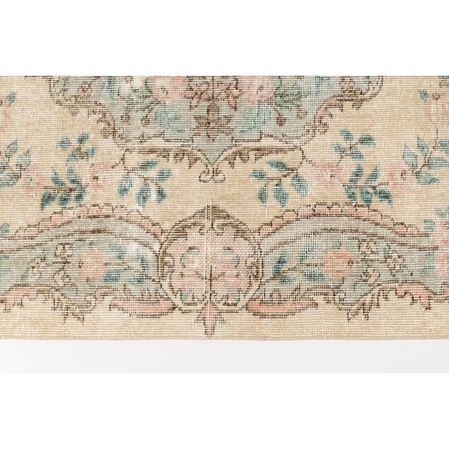 This is a vintage Turkish Oushak rug from the Mid 20th Century. The piece was hand-knotted.