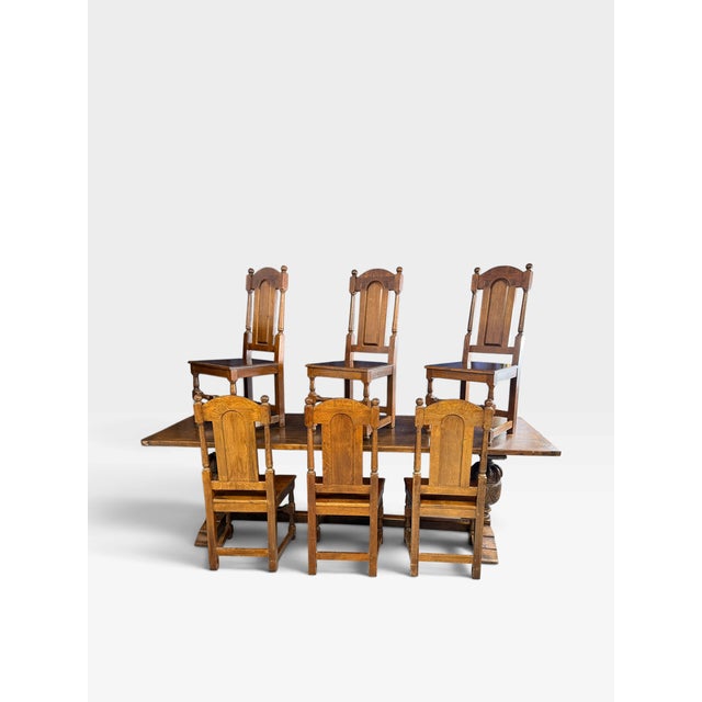 This antique Elizabethan Jacobean style solid oak refectory dining table, accompanied by six chairs, dates to...