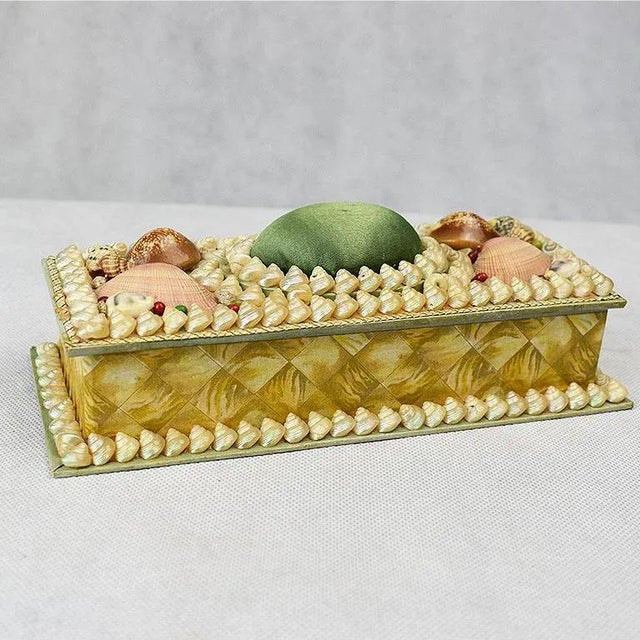 Long rectangular shell encrusted box. Carefully applied shells decorate the top and bottom edges of this green board box...