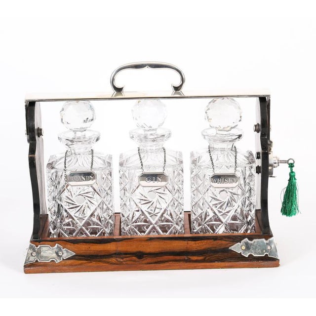 This is a superb antique Edwardian coromandel cased three decanter George Betjemann’s & Sons patent tantalus, with...