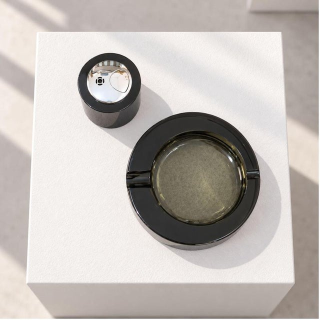 A refined Italian smoking set from the 1970s crafted from smoked Murano glass, comprising a circular ashtray and a...