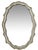 Solid cast metal oval mirror in a scalloped cartouche form. Silver-gilt finish — a warm amalgam of silver finish with a...