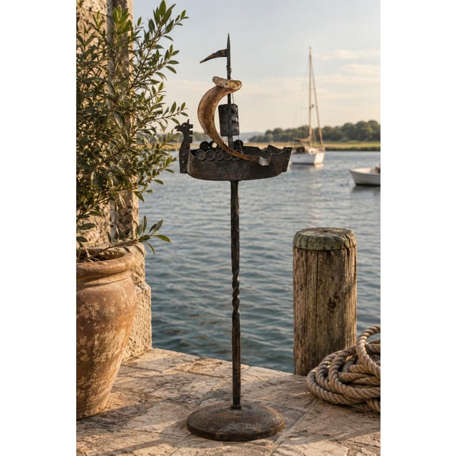 An exceptionally sculptural vintage wrought iron floor ashtray fashioned as a stylized sailing ship, dating to the 1920s....