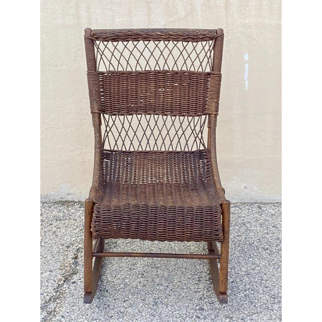 Antique Victorian Wicker and Rattan Wooden Small Rocking Chair Rocker. Item features a solid wood wicker wrapped frame,...