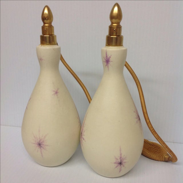 A pair of mid-century Atomic DeVilbiss Atomizers. Cream white blown glass bottles with chartreuse and black starbursts....
