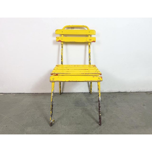 This yellow chair was made in former Czechoslovakia during the 1960. It features an iron construction and a wooden seat...