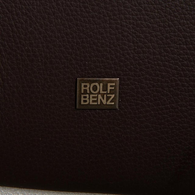 The two-seater from the 3300 series by Rolf Benz is covered in brown genuine leather and stands on tapered legs made of...