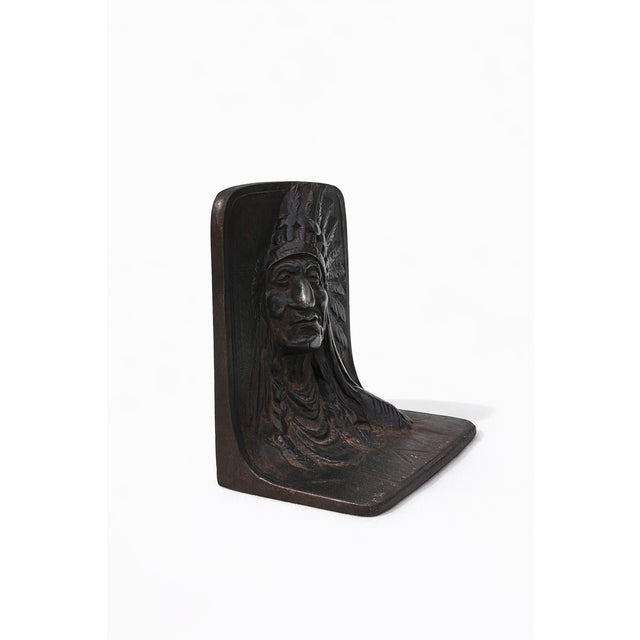 Vintage cast iron bookend featuring a detailed Native American chief bust in relief form. The piece has a rich dark finish...