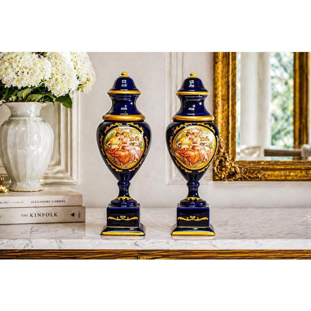 A beautifully matched pair of hand-painted porcelain urns, these elegant pieces capture the timeless refinement of...