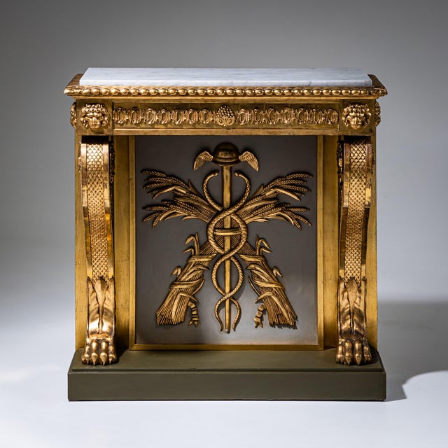 Swedish wall console in gilt and stuccoed wood with rich Neoclassical decoration. At the center appears an Aesculapian...
