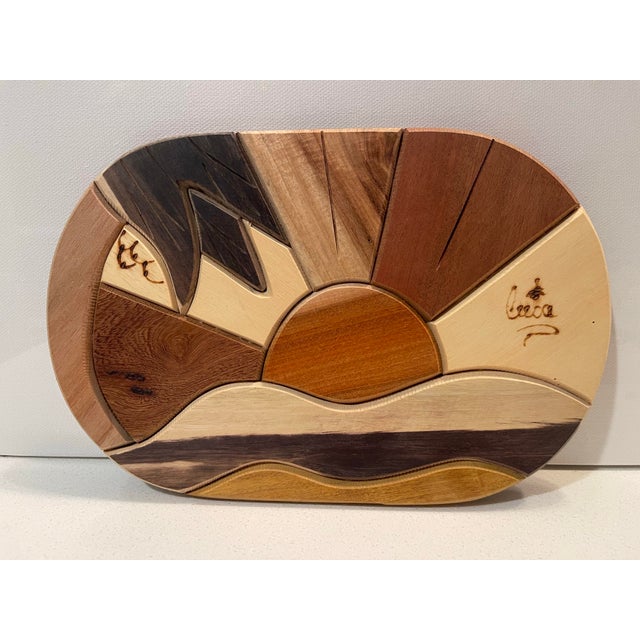 This handcrafted wooden piece is an example of intarsia or marquetry, where various types of natural wood are shaped and...