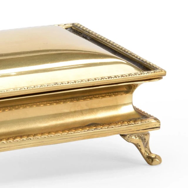 Small polished brass box with hinged lid and decorative detailed trim.