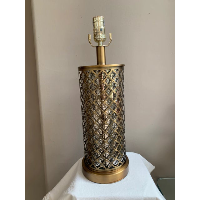 Hollywood Regency table lamp with an open, geometric lattice body made out of brass metal. Underneath the lattice work is...