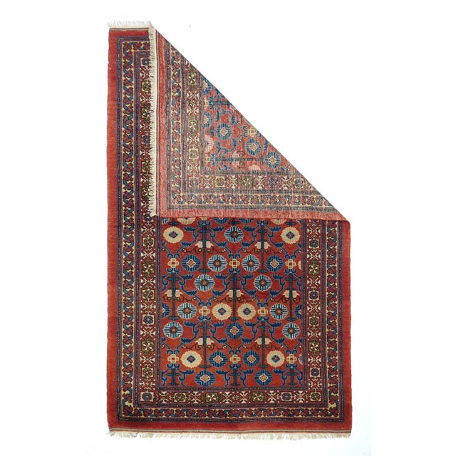 The warm rust-red field with a touch of orange, shows offset large triple posy flowers with blue leaves in a textile...