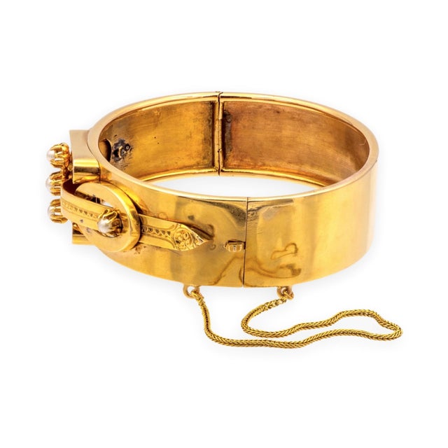 A solid 14K yellow gold hinged bangle from the Victorian Aesthetic period, set with five round seed pearls approximately...