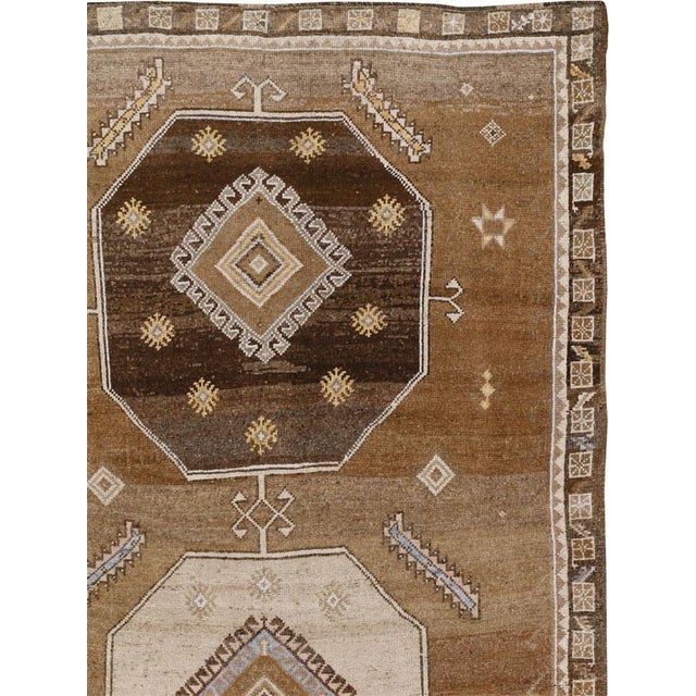 This Mid-20th century Turkish Anatolian room-size carpet presents a spacious geometric composition arranged across a warm...