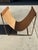 Elevate your living space with this sculptural contemporary magazine rack featuring a rich cognac saddle leather sling...