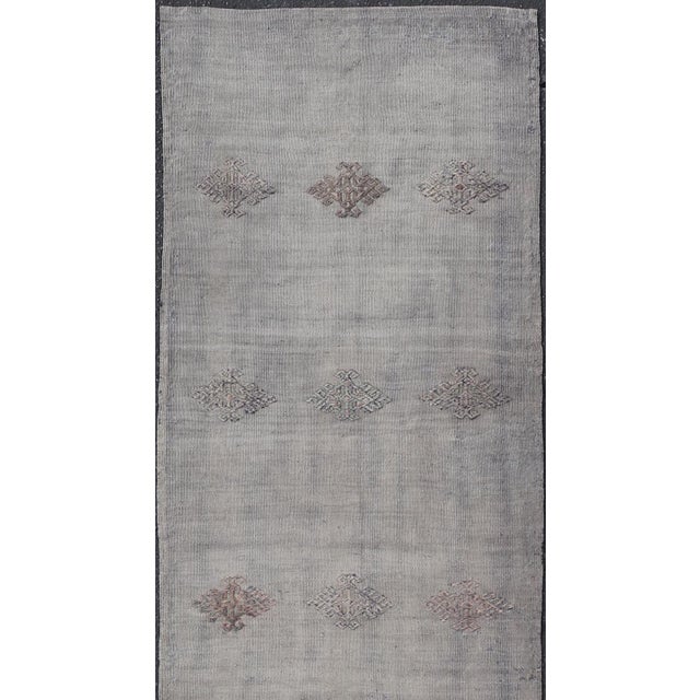 Measures: 2'4 x 9'9 This Vintage Turkish Kilim Runner offers a refined elegance with its muted color palette and intricate...