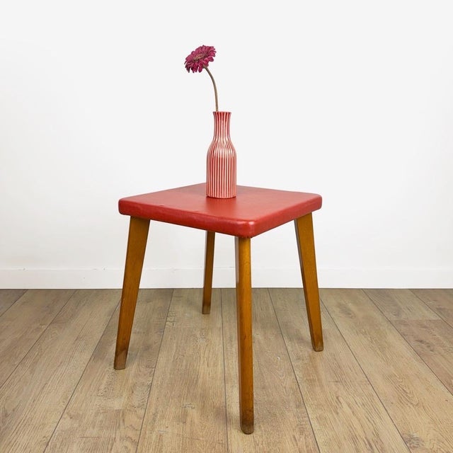 This modernist stool from the 1950s features an elegant square seat upholstered in red faux leather. The base, composed of...