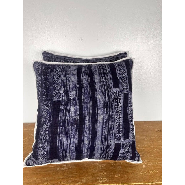 A striking pair of decorative pillows crafted from richly patterned batik textiles, featuring deep indigo and charcoal...