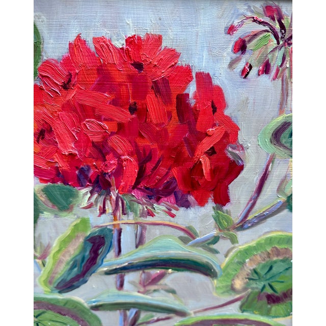 Vintage oil painting on hardboard depicting a bright red geraniums and green leaves against a soft blue background. By...