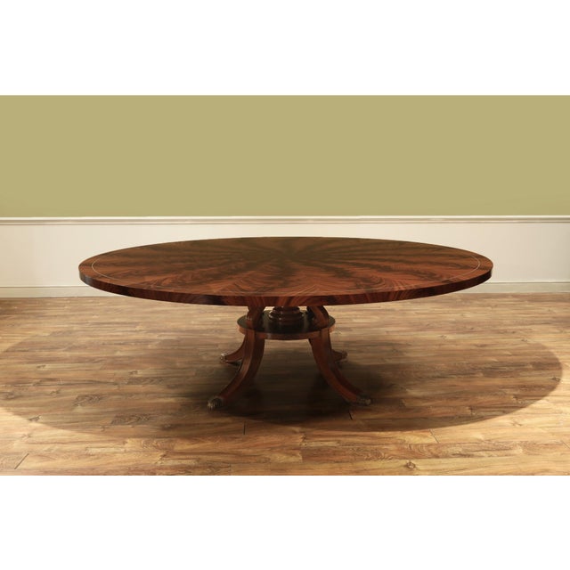 90-inch round flame mahogany dining table. Features a 1.5-inch-thick flame mahogany tabletop supported by an outswept...