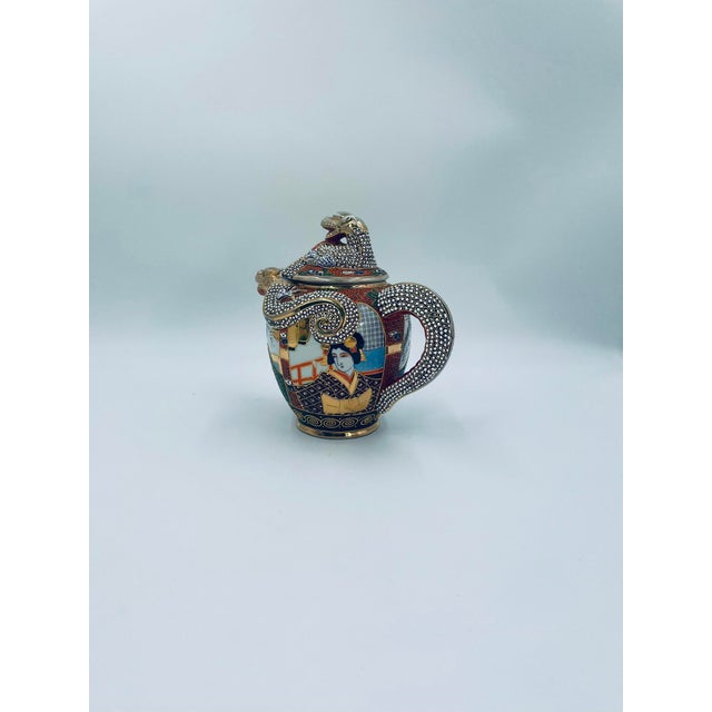 A teapot produced in Japan between the 1930s and 1950s in the opulent Satsuma, Kutania style, crafted from high-quality,...