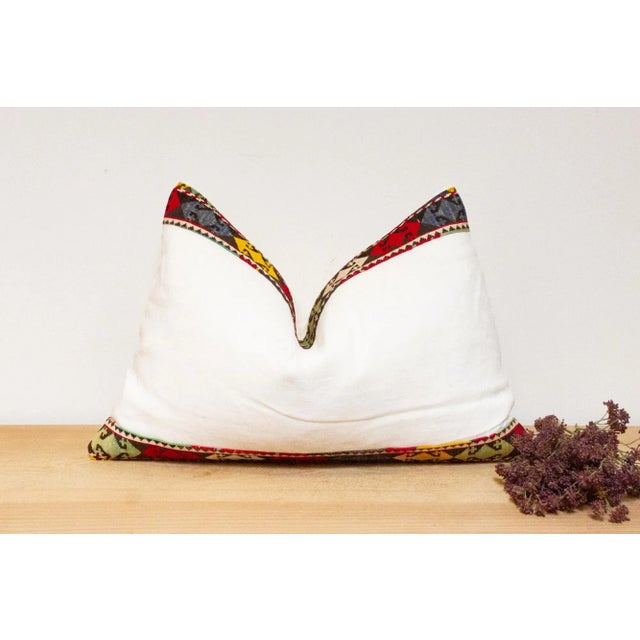 This handcrafted pillow features a vibrant, hand-stitched textile border created by the Lakai tribe of Uzbekistan. It is a...
