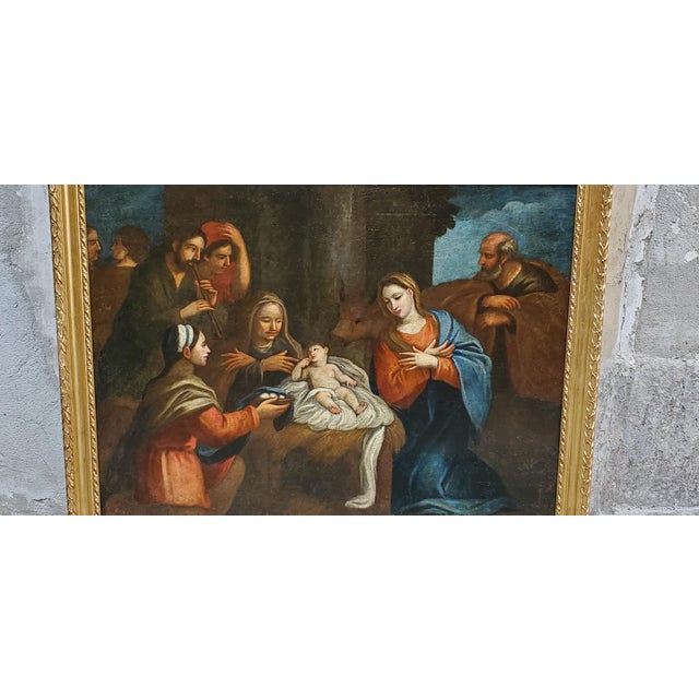 Oil painting on canvas depicting the Adoration of the Magi. In the center, the baby Jesus lies on a white cloth, flanked...