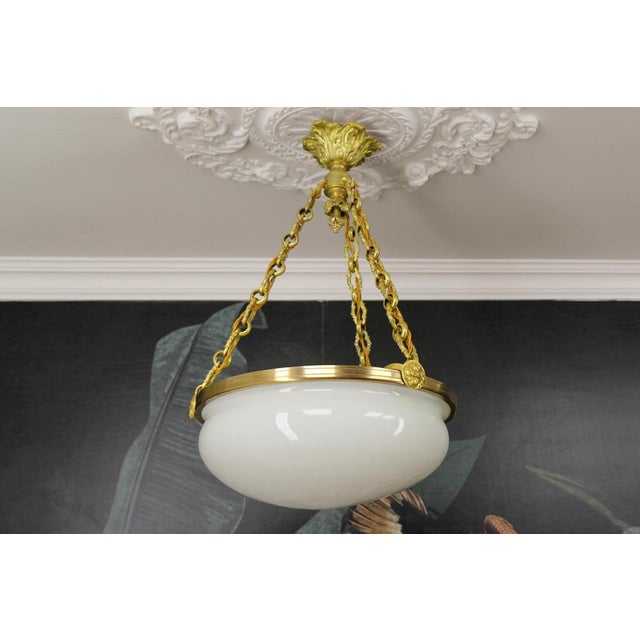 Antique French Louis XVI style white glass, brass, and bronze pendant chandelier from ca. 1920. This stunning French...