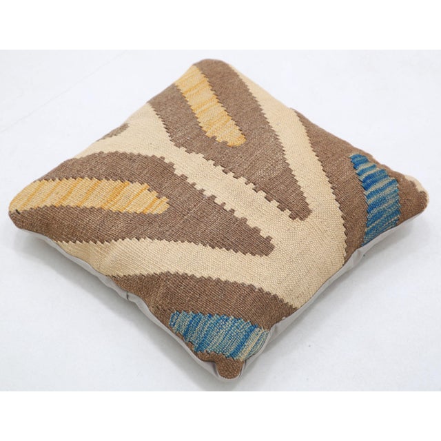 A one-of-a-kind handwoven Afghan wool kilim accent pillow featuring oversized zigzag chevrons in brown and cream with blue...
