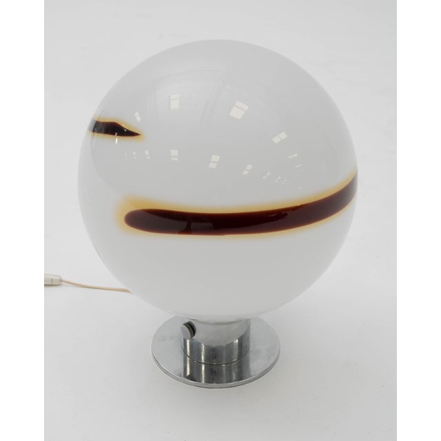 A table or bedside lamp with a spherical globe, reminiscent of the avant-garde creations of Italian firms like Mazzega or...