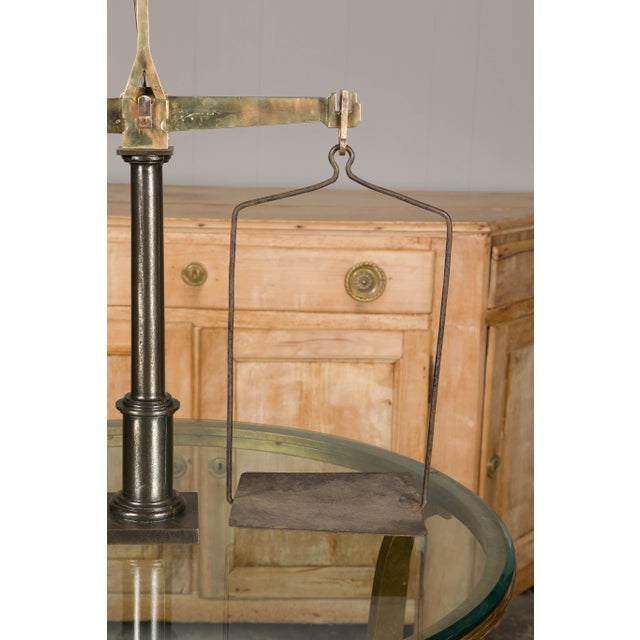 A French brass and steel scale from the 19th century with central column and two weighing pans. Embrace the charm and...