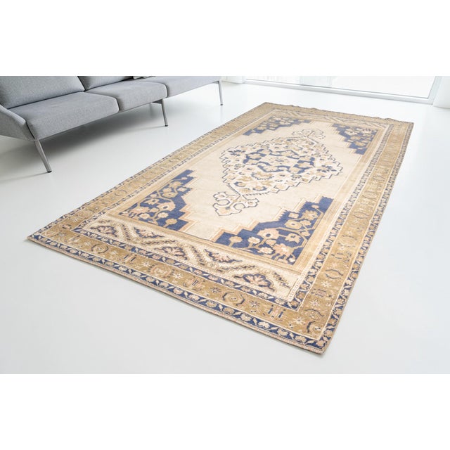 This is a vintage Turkish Oushak rug from the Mid 20th Century. The piece was hand-knotted.