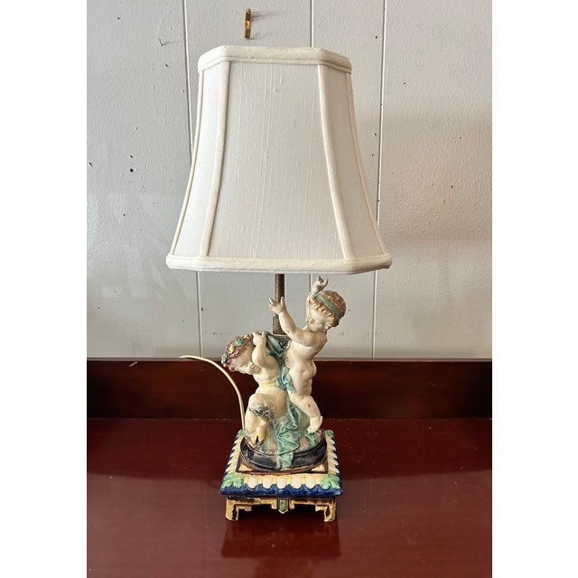 Vintage Porcelain Cherub Table Lamp. A porcelain figural table lamp featuring cherubs or putti figures, similar in style...