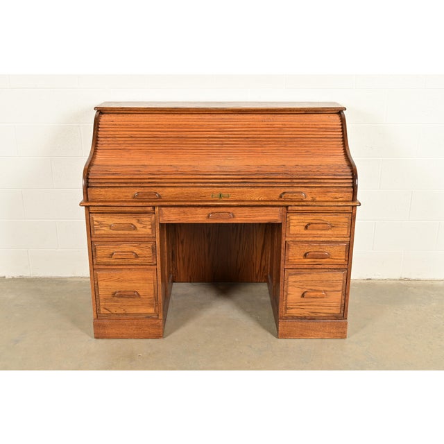 A gorgeous Victorian or Edwardian style solid oak roll-top desk USA, Circa Late 20th Century Carved oak, with brass...