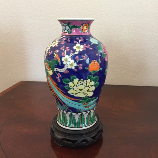 Beautifully painted early 20th Century porcelain vase. Bird and flower design with carved wooden base.