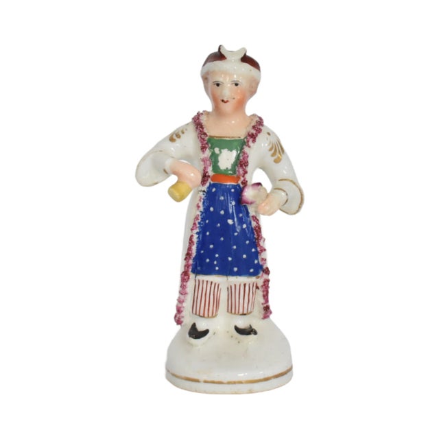 An antique Staffordshire figurine of a Turk or man dressed "a la turquoise" in a white coat gold details and red trim with...