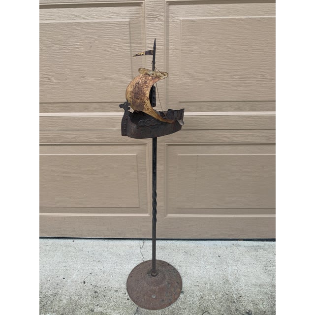An exceptionally sculptural vintage wrought iron floor ashtray fashioned as a stylized sailing ship, dating to the 1920s....