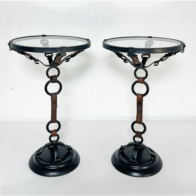 A pair of side tables featuring a trompe l'oeil framework of equestrian harnesses rendered in steel with genuine leather...