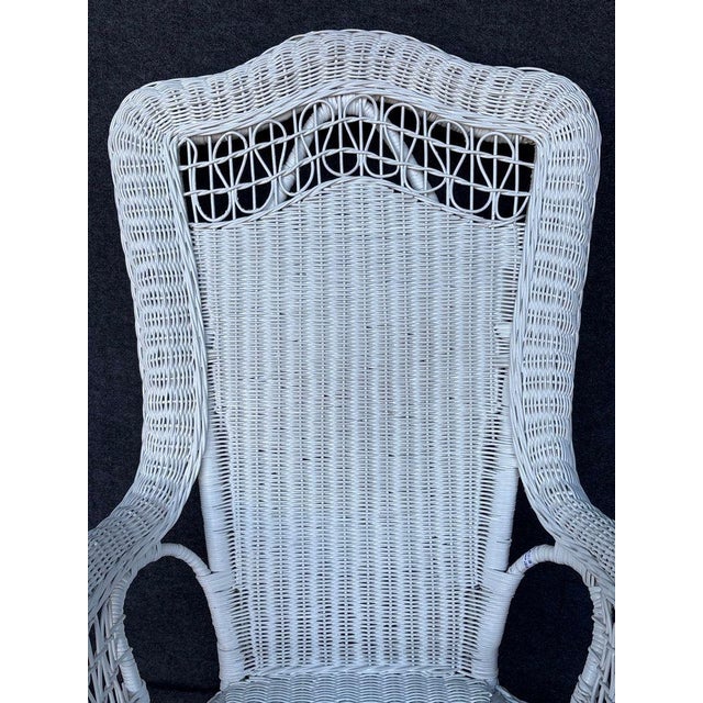 A pair of antique white wicker Victorian style rocking chairs, fully assembled and made in the United States in the late...