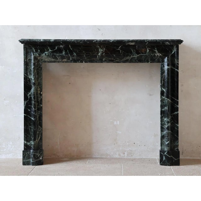 This refined antique marble fireplace is crafted from deep green marble that appears almost black, featuring delicate...
