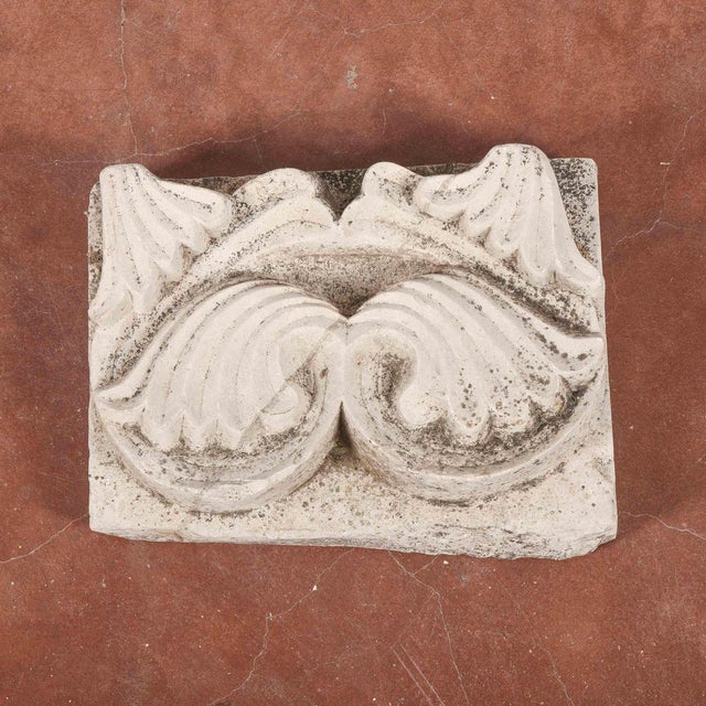 This ancient stone fragment has a sculptural decoration, probably part of a larger architectural element or wall covering....
