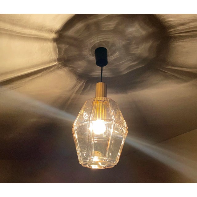 Large pendant light by limburg, featuring an oversized polyhedral glass shade with highlighted edge, polished brass...