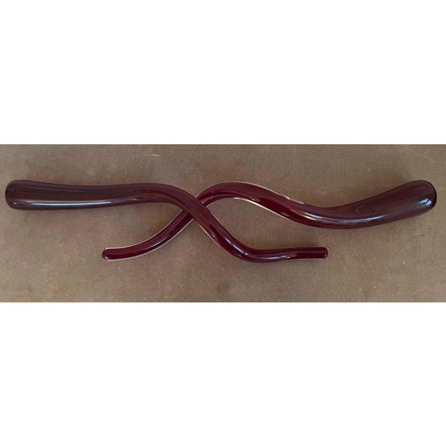 Pair of red glass decorative objects that can be displayed individually or intertwined. Long, twisted and tapered shape....