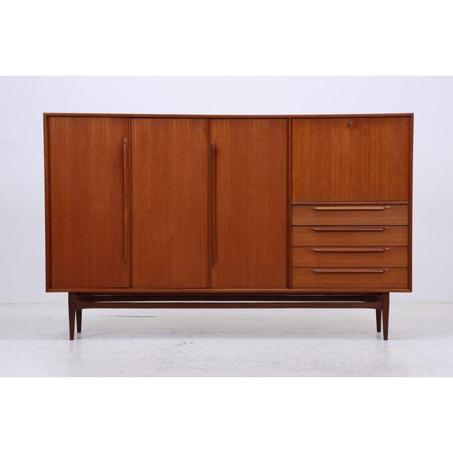 Teak highboard by Heinrich Riestenpatt from the 1960s. The minimalist front with its long handles and finely crafted legs...