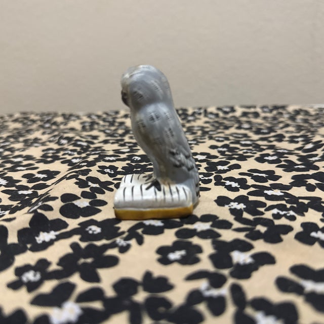 A whimsical and detailed miniature sculpture of a majestic Snowy Owl. The bird is depicted with textured gray and white...