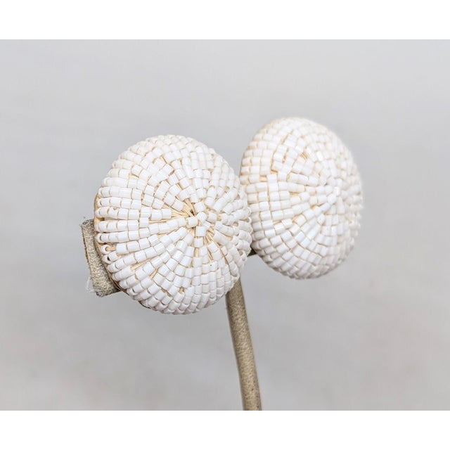 1960s goldtone round domed tiny white beaded butterfly clip back earrings. Marked "NAPIER PAT. PEND." on the clips....