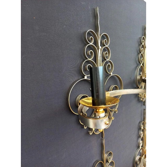 Suite of four sconces in gilded and nickel-plated brass, two arms of light, rich ornamentation of volutes. The assembly is...